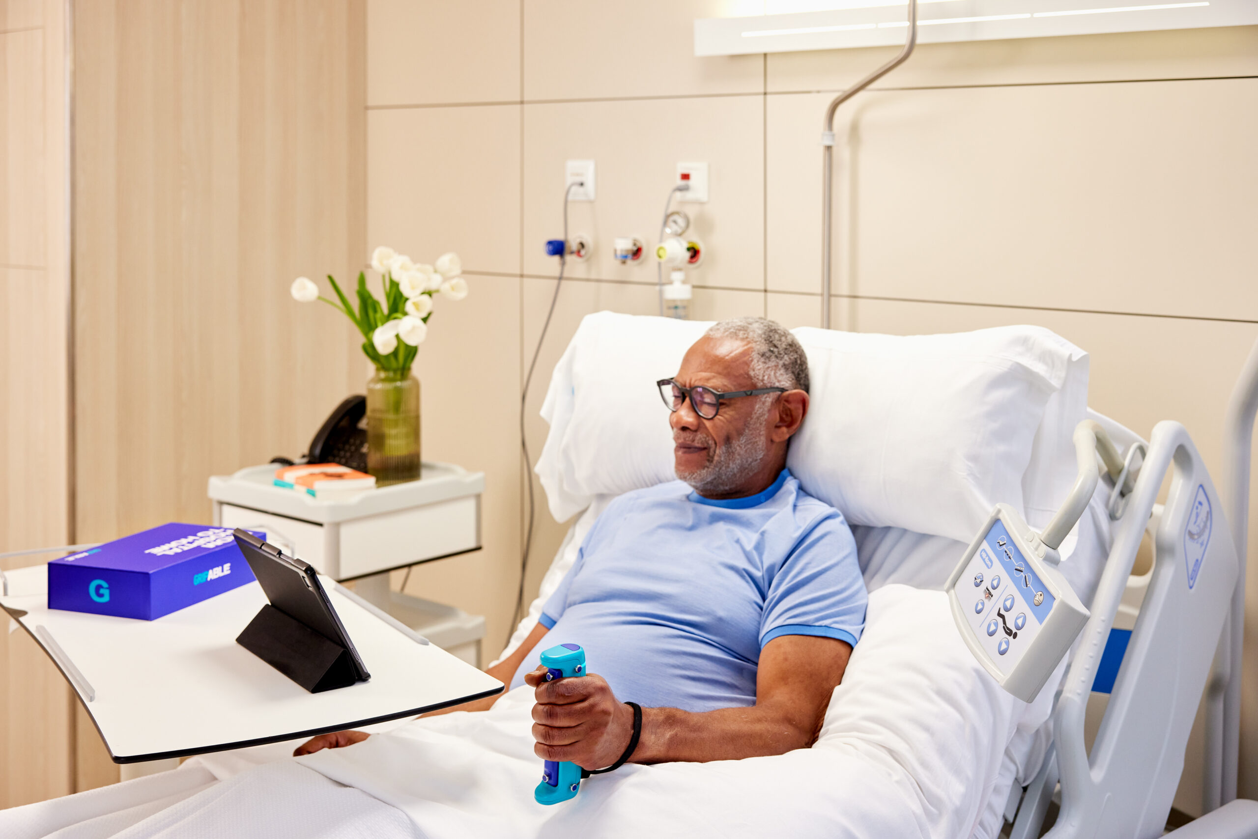 Older gentleman in hospital bed using GripAble alone