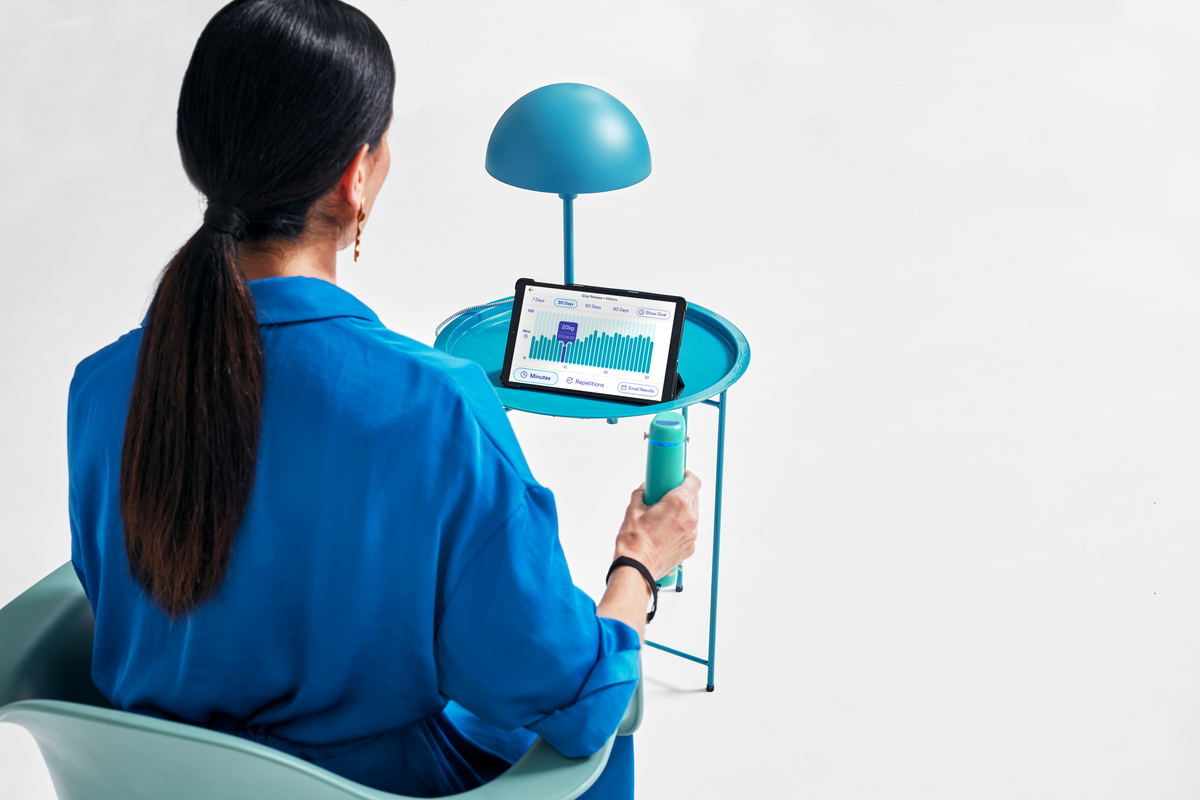 behind a seated woman using a hand dynamometer, grip strength and renal disease