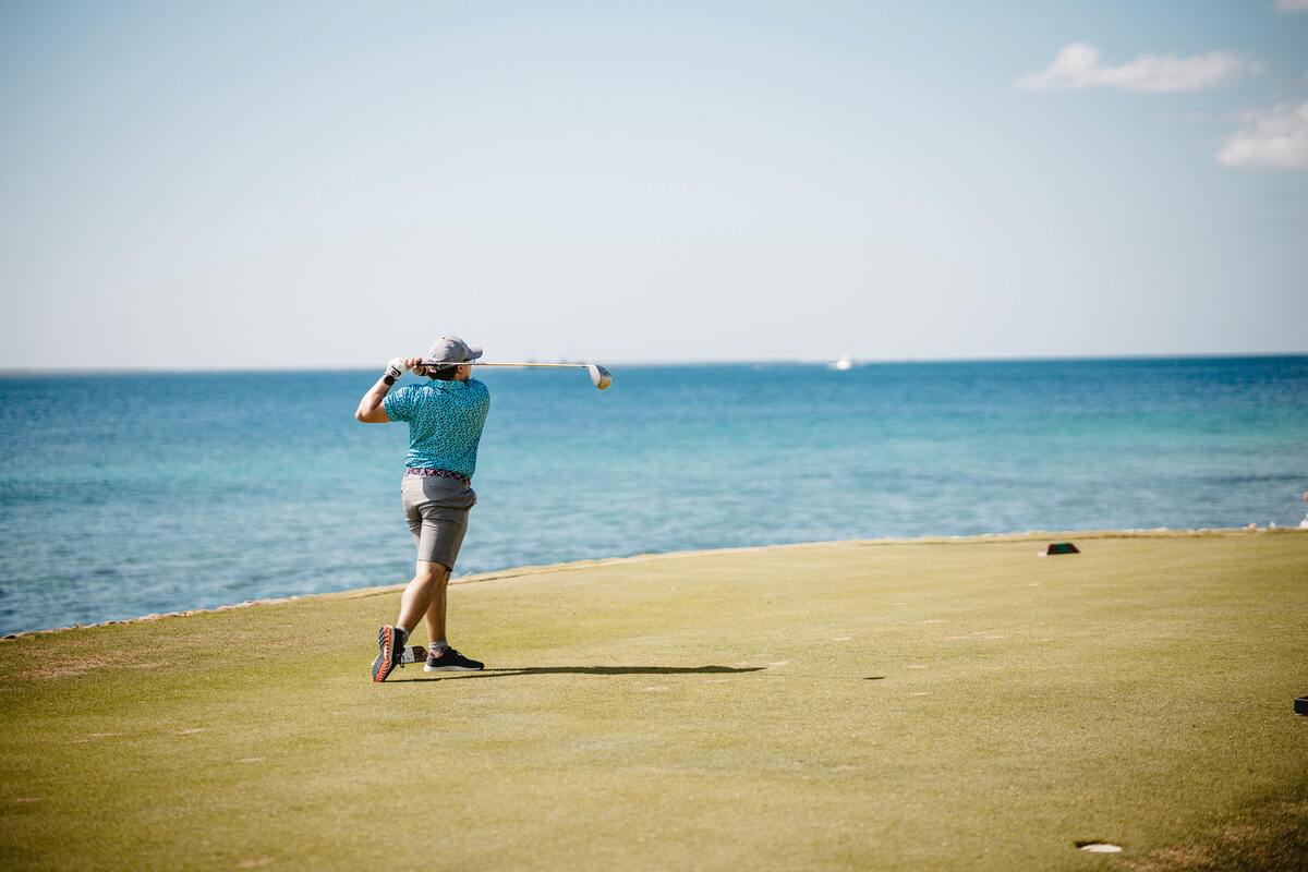 man playing golf by sea, grip strength and sport