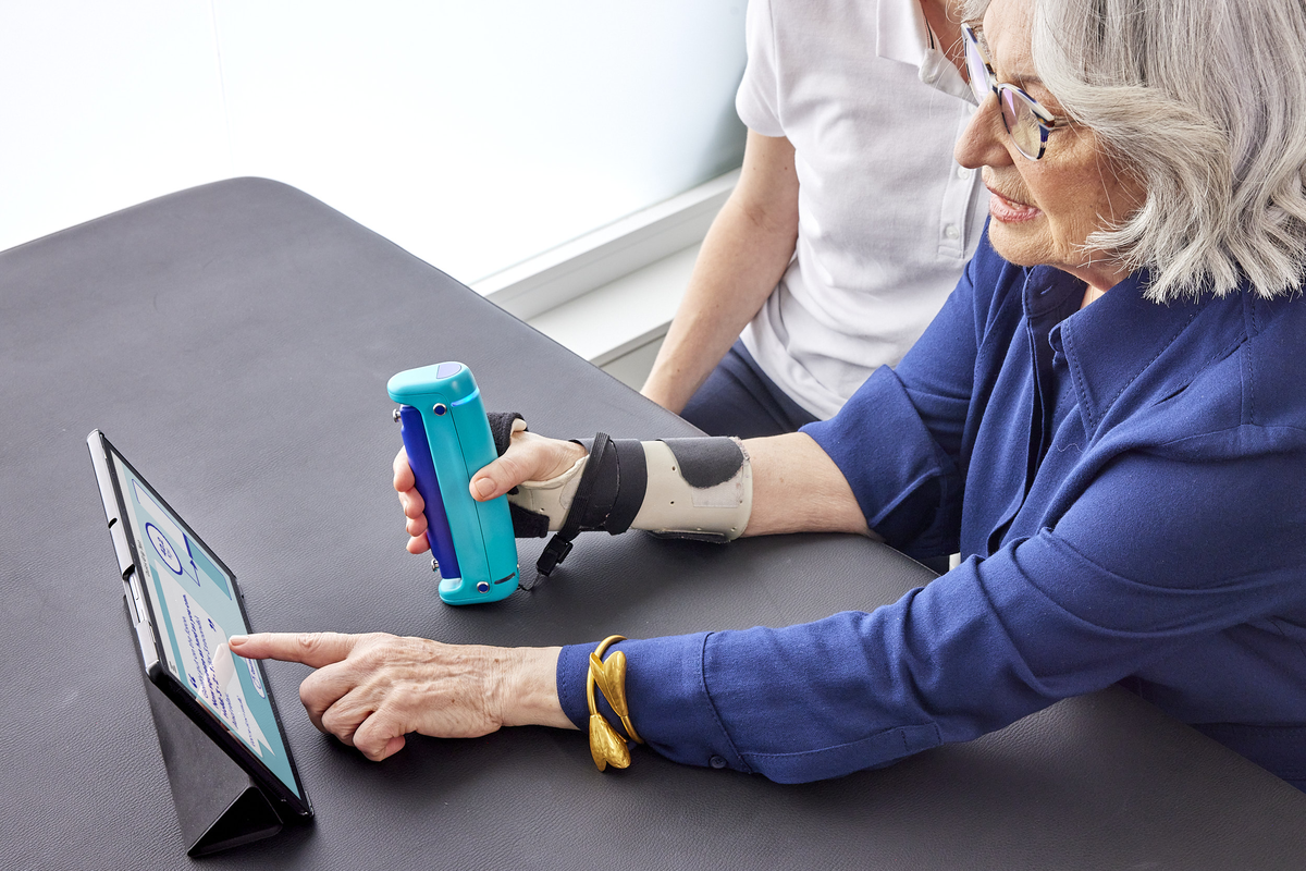 woman in a clinic using a tablet and hand dynamometer, next steps for older adults flagged as a fall risk